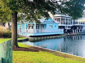 A waterfront property with a house featuring a balcony and a dock extending into the water. - Cozy Teal site N111 Ocean Lakes home close to everything Ocean Lakes! (Myrtle Beach)