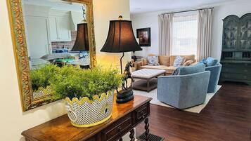 A living room with a wooden console table, a lamp, a sofa, and a large mirror.