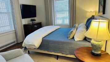 A hotel room with a bed, a TV, a lamp, and a view of the outside through the window.
