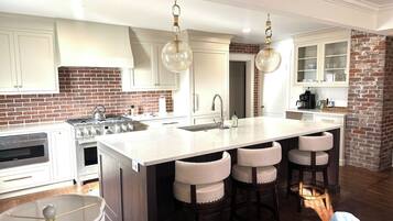 A kitchen with a large island, bar stools, a brick accent wall, and modern appliances.