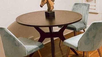 A round table with a horse sculpture centerpiece, surrounded by four light blue chairs with wooden legs.