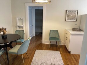 A dining area with a round table and chairs, a white cabinet, and a door leading to another room. - Broadway BNBs I - 1 BR Apartment - Walk to Centre (Danville)