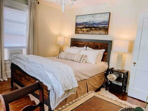 A bedroom with a bed, bedside lamps, a painting, and a window with curtains. - Broadway BNBs I - 1 BR Apartment - Walk to Centre (Danville)
