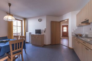 Ett kompakt kök med en matplats, en liten tv och en klocka på väggen.