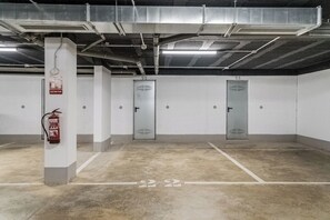 A parking garage with concrete floors, numbered parking spaces, and fire extinguishers. - Green Fairway by IIM (AN)