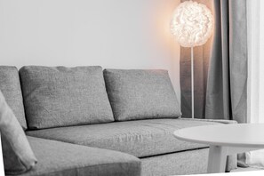 A grey sofa with a round light fixture above it. - Green Fairway by IIM (AN)