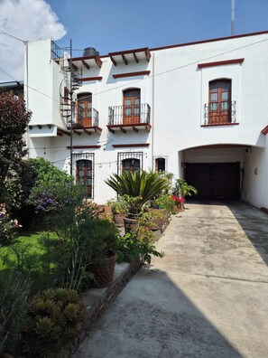A two-story building with a garage, potted plants, and a clear sky.