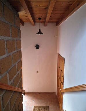 A staircase with a wooden handrail, a brick wall, a ceiling light, and a door. - "Juárez Loft" (Amecameca de Juárez)