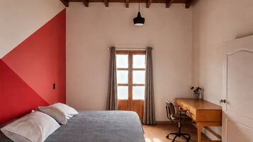 A bedroom with a bed, a desk, and a chair.