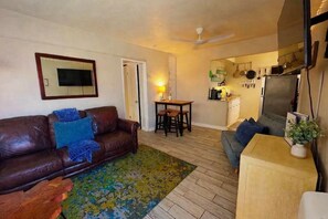 Ein Wohnzimmer mit braunem Ledersofa, einem Couchtisch und einem Essbereich mit Tisch und Stühlen.