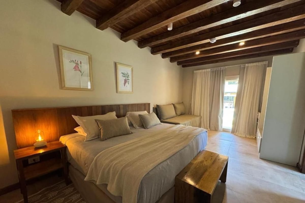 A bedroom with a large bed, wooden headboard, bedside tables, and a bench.