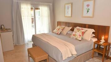 A bedroom with a bed, bedside table, bench, and a view of the outside.