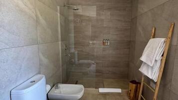 Un baño moderno con ducha acristalada, inodoro y bidé.