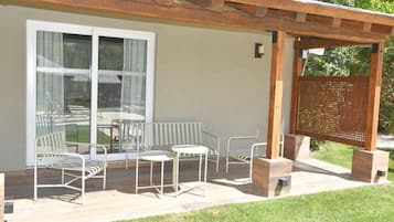 Un patio al aire libre con una pérgola, una mesa y sillas.