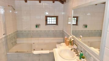 Un baño con bañera, lavabo, espejo y ventana.