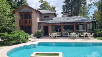 A two-story house with a swimming pool, outdoor seating, and a covered patio.