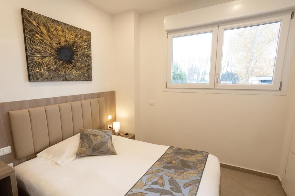 Une chambre d  ’hôtel avec un lit, une table de chevet, une œuvre d’art accrochée au mur et une fenêtre.