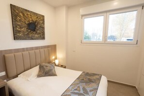Habitación de hotel con cama, mesita de noche, una obra de arte en la pared y ventana.