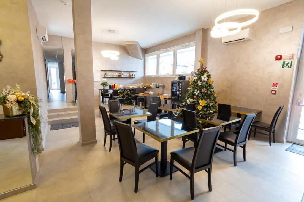 Un comedor con una mesa de vidrio rodeada de sillas, un árbol de Navidad y una cocina al fondo.