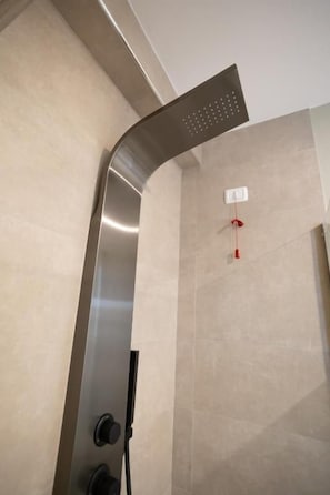 Una dutxa moderna amb un disseny corbat, un panell de control i una sortida d'aigua visible.
