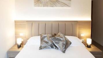A hotel room with a large bed, a headboard, bedside lamps, and a wall-mounted artwork.