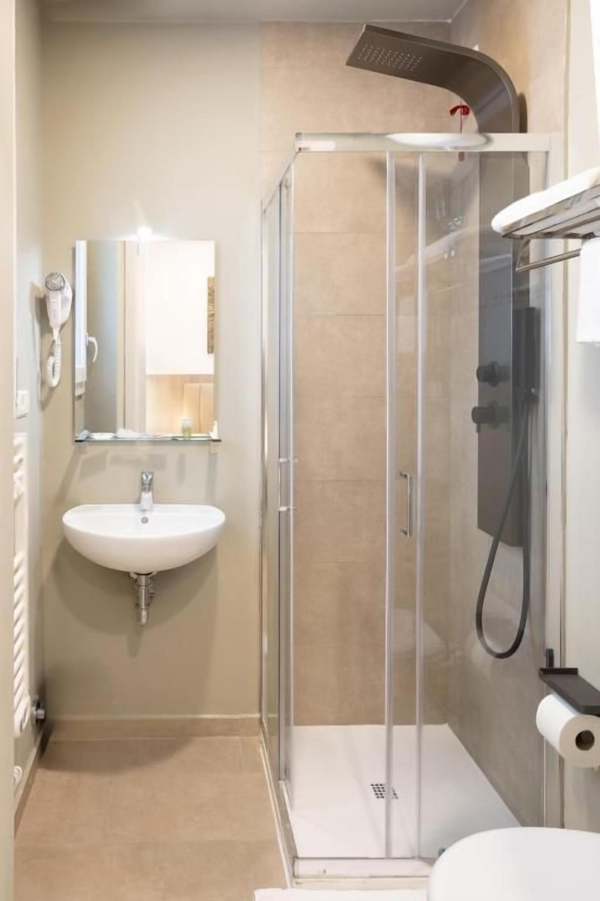 Un baño con ducha de vidrio, lavamanos e inodoro.