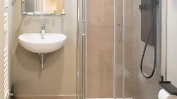 Un baño con ducha de vidrio, lavamanos e inodoro.
