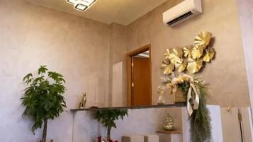 A reception area with a modern design, including a reception desk, potted plants, and a decorative wall piece.