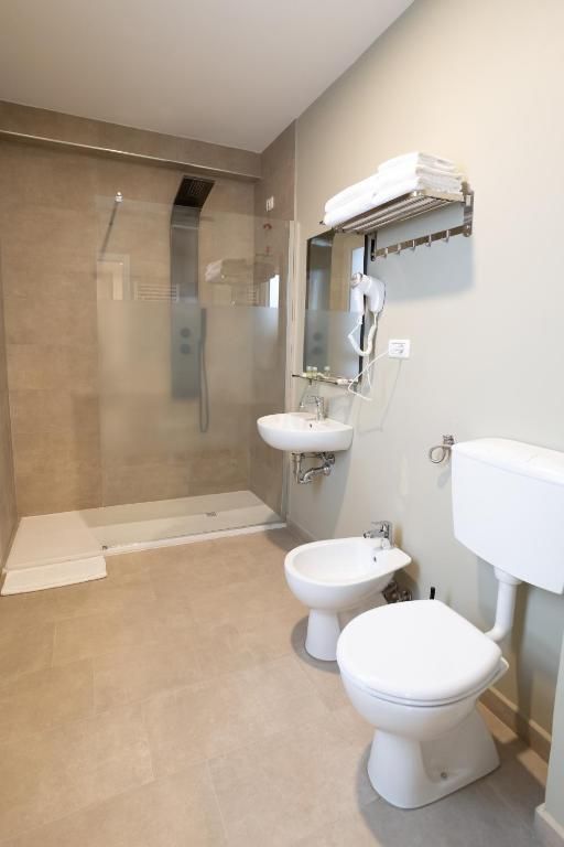 A bathroom with a glass-enclosed shower, a sink, a bidet, and a toilet.