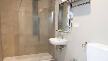 A bathroom with a glass-enclosed shower, a sink, a bidet, and a toilet.