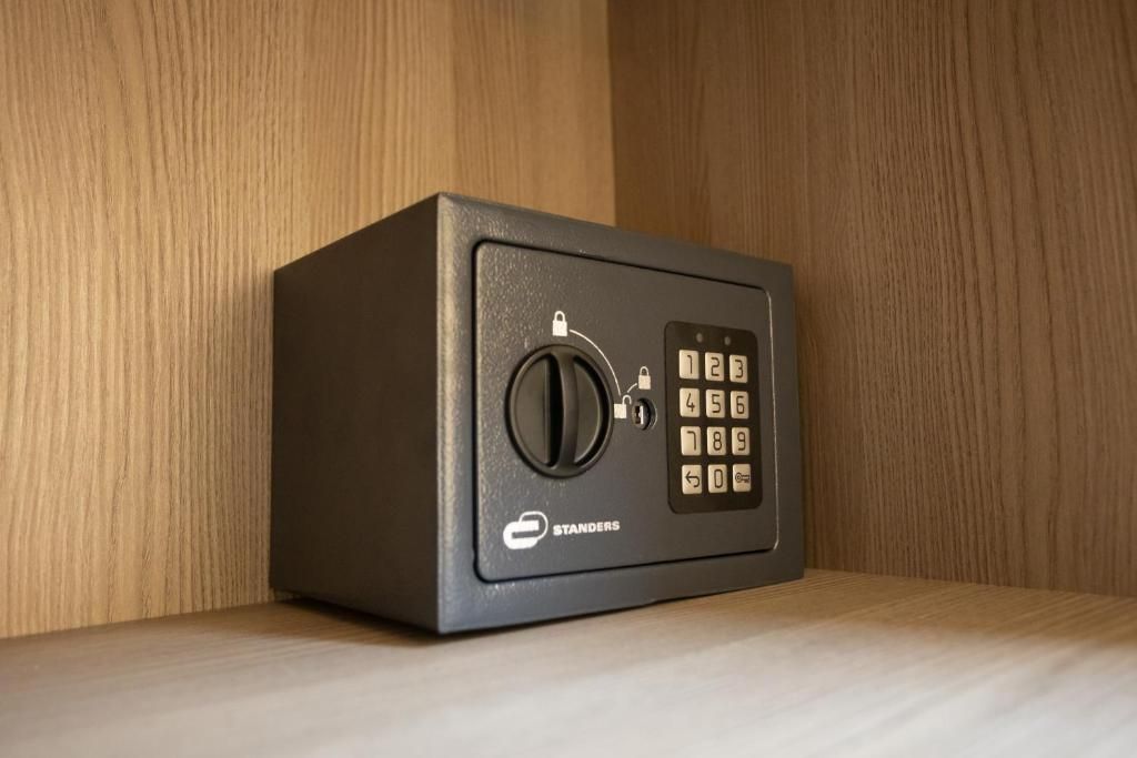 Una caja fuerte negra con un dial de combinación y una cerradura, sobre una superficie de madera.