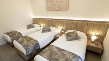 Una habitación de hotel con dos camas, cada una con cabecera, lámparas de noche y almohadas decorativas.
