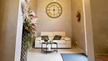 A hallway with a white sofa, a round wall clock, and a decorative plant.