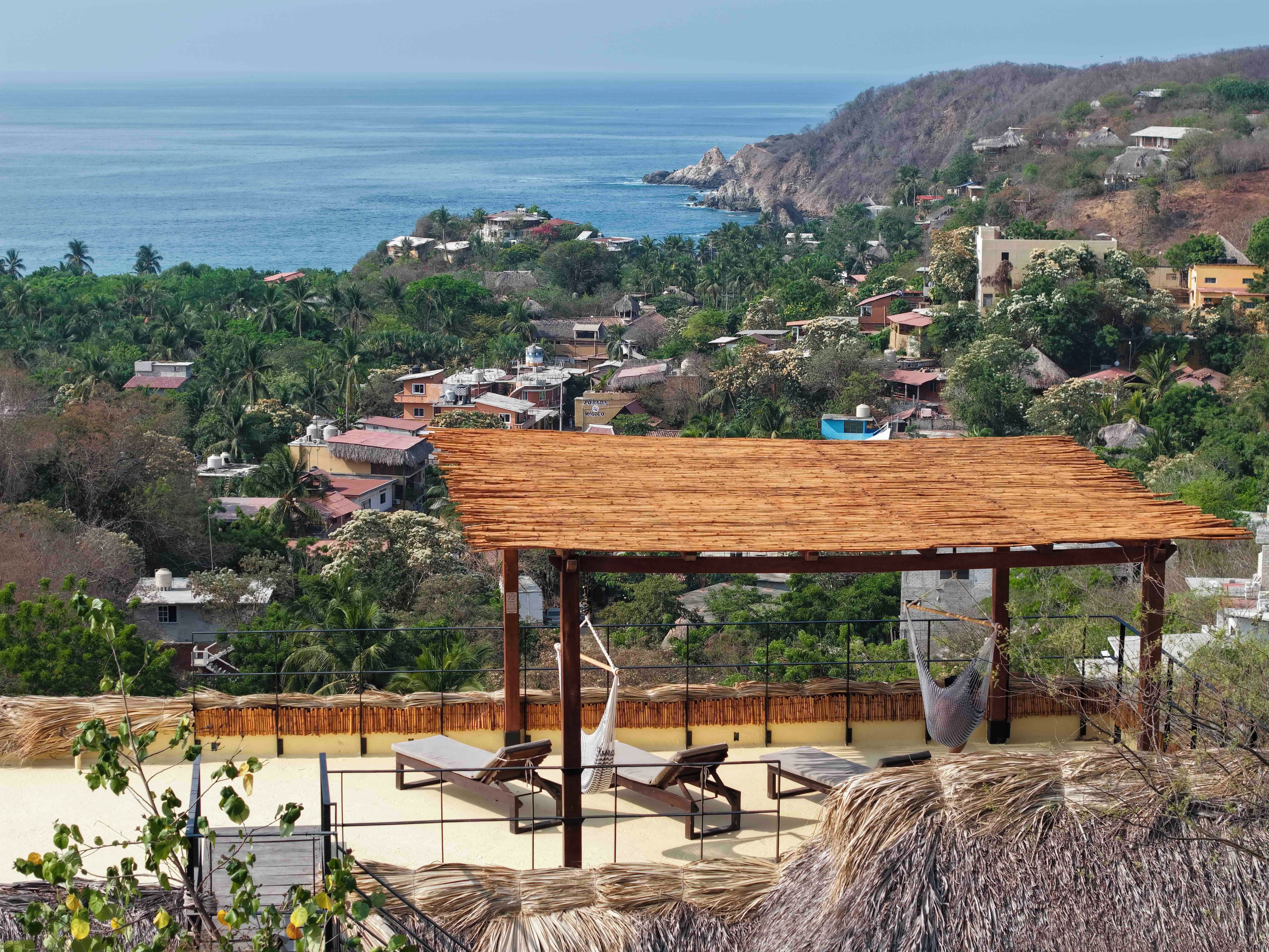 A beachside view with a wooden structure, lounge chairs, and a hammock.
