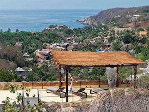 Vista de la playa con una estructura de madera, sillas de descanso y una hamaca.
