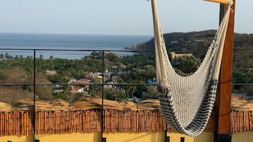 A hammock on a balcony overlooking a coastal town.
