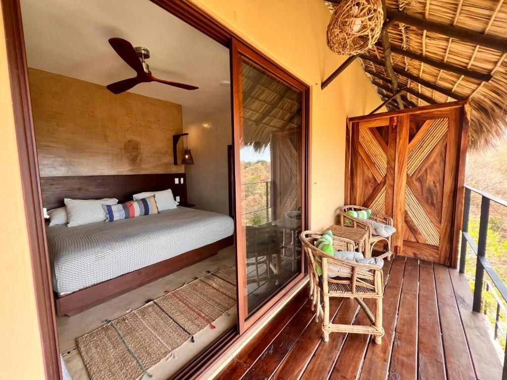 Una habitación con una cama, un ventilador de techo, una cesta tejida y una puerta de madera.
