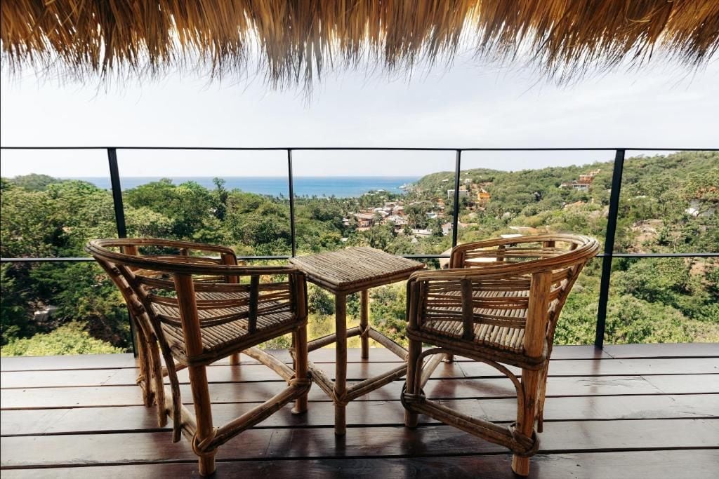 Un balcón con muebles de mimbre con vistas a un paisaje costero.