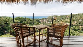 Un balcón con muebles de mimbre con vistas a un paisaje costero.