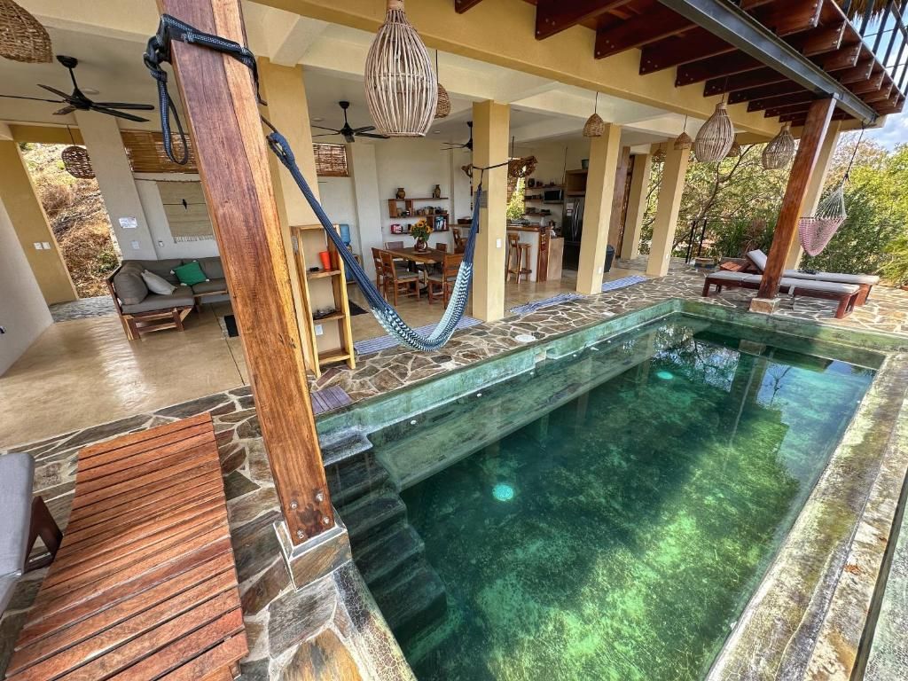 A pool area with a stone wall, wooden deck, and lounge chairs.