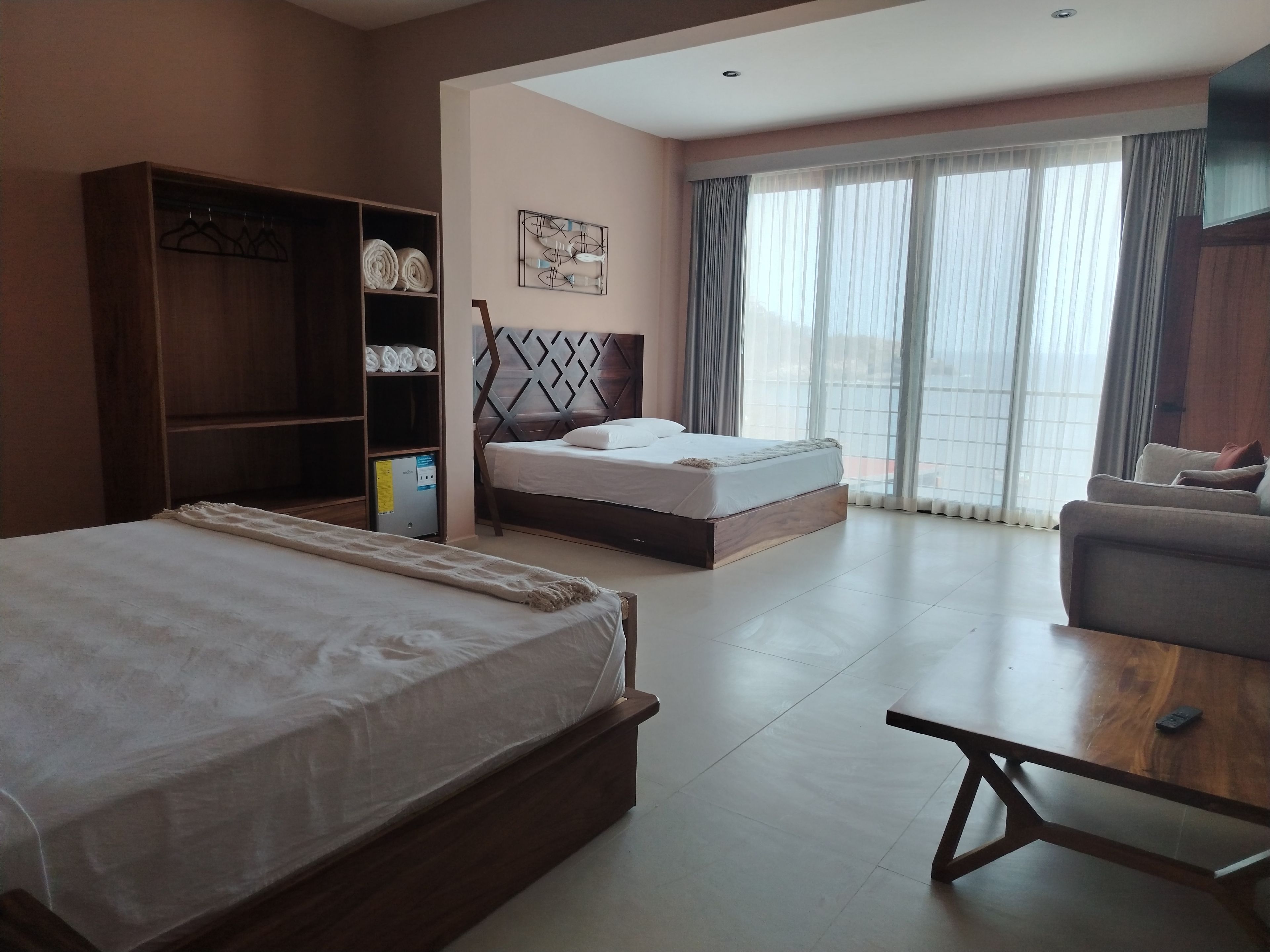 Una habitación de hotel con una cama grande, un sofá, una mesa de madera y un armario.