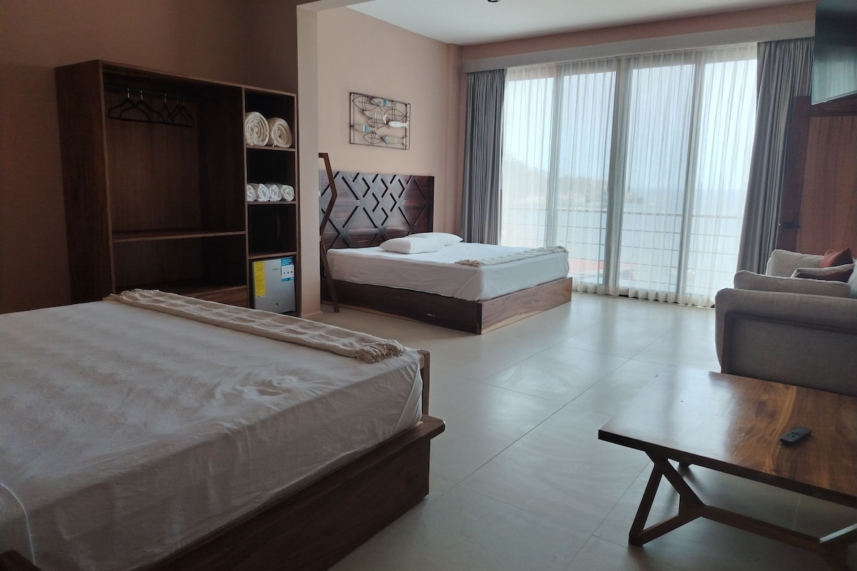Una habitación de hotel con una cama grande, un sofá, una mesa de madera y un armario.