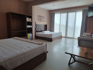 Una habitación de hotel con una cama grande, un sofá, una mesa de madera y un armario.