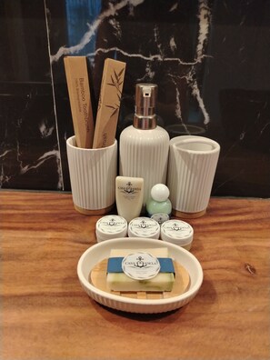 A bathroom vanity with a bamboo toothbrush holder, a bottle of liquid soap, and several toiletry jars.