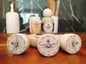 A collection of hotel toiletries including a shampoo bottle, a soap bar, and several containers of body wash. - Casa Ancla (San Pedro Pochutla)
