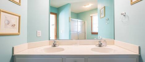 A bathroom with two sinks, a large mirror, and framed pictures on the wall.