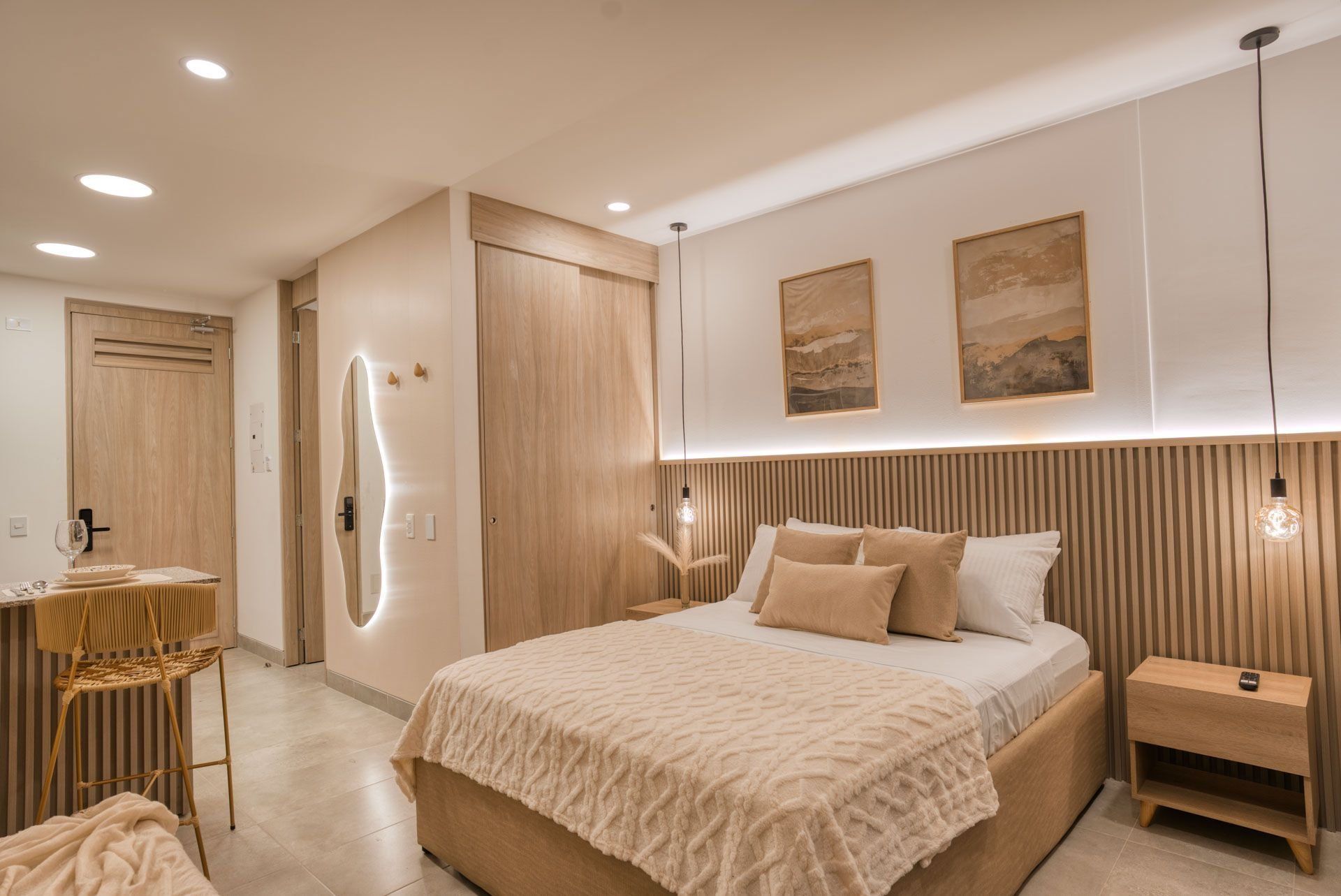 A modern bedroom with a large bed, bedside tables, a chair, and artwork on the wall.