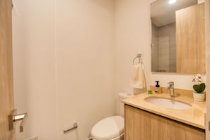 A bathroom with a toilet, sink, and mirror.