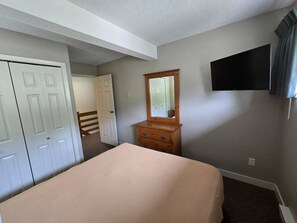 A bedroom with a bed, a dresser, a mirror, a television, and a closet. - Alpine Escape | Ski-In/Out | Toby Chair | Pools (Panorama)