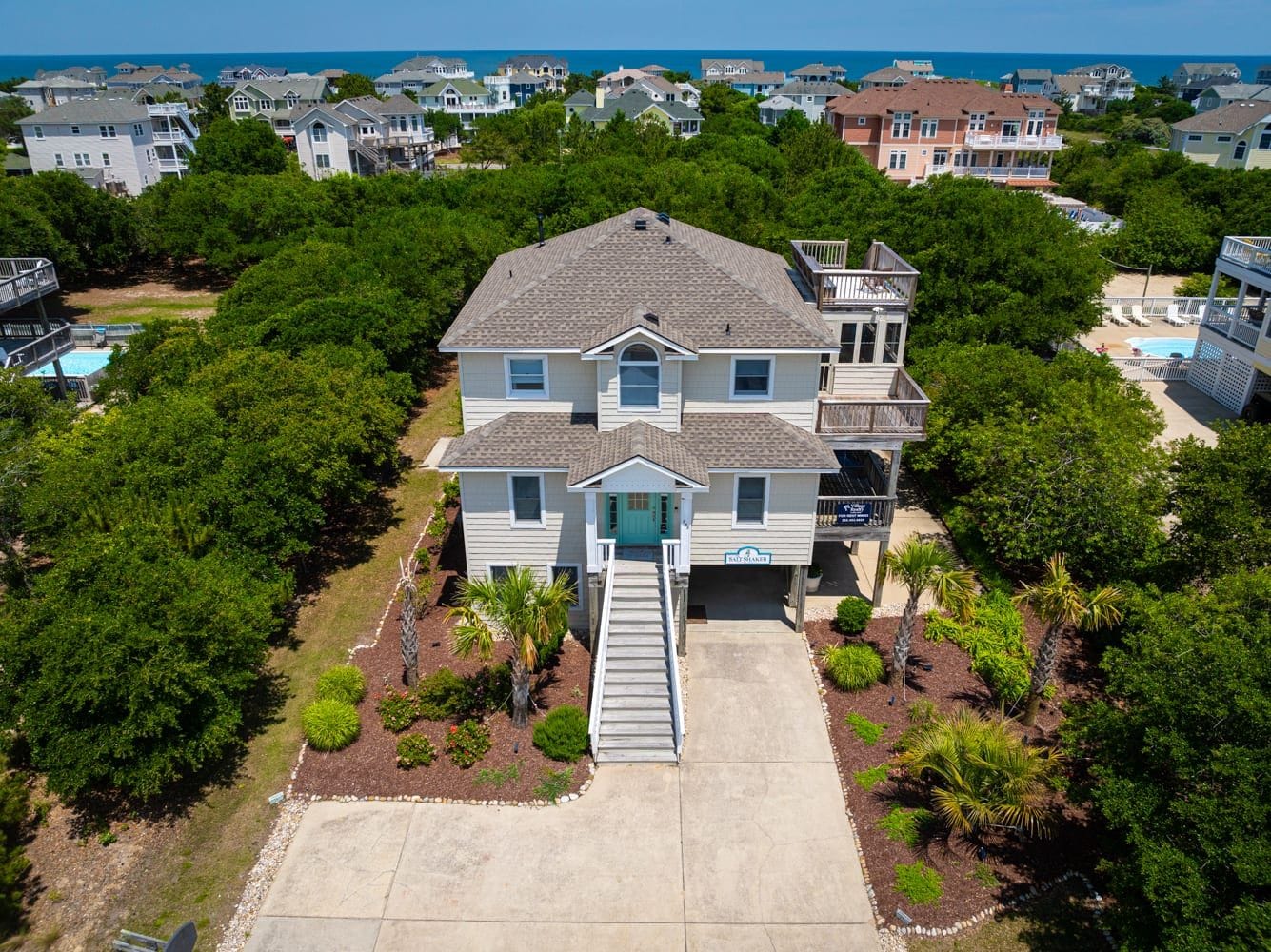 A two-story house with a front porch, a visible garage, and a swimming pool in the background.
